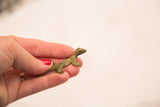 Small vintage bronze lizard figure with a green patina held to show scale.