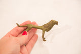 Hand holding a detailed vintage male lion bronze sculpture with aged patina.