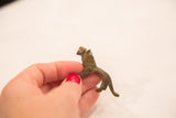 Small vintage bronze lion figurine held to show its scale and oxidized patina.