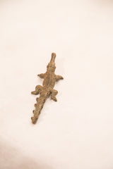 The detailed scaly body of a vintage dark bronze crocodile gold weight.
