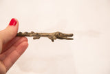 Dark bronze crocodile sculpture with dark patina, held by a hand.