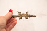 Vintage bronze crocodile gold weight held in hand, showing scale and textured surface.