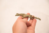 A hand holding the vintage bronze crocodile sculpture, showing its texture and scale.