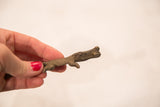 Textured African bronze crocodile gold weight held in hand.