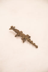 Angled view of a handmade bronze crocodile gold weight showing its detailed, scaly body and tail.