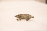 The base of a vintage bronze porcupine sculpture showing its feet and oxidized patina.