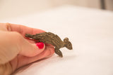 A hand holding the vintage bronze porcupine sculpture, illustrating its petite scale.