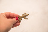 Vintage bronze lizard gold weight held in hand to demonstrate its small size.