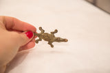 Aged bronze vintage African crocodile gold weight held gently in a hand.