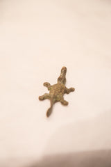 The textured, patinated form of a vintage bronze crocodile gold weight.