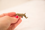 Small vintage bronze rhino gold weight held in hand, showing its patina.
