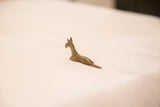 The simple, elongated form of a handmade bronze zebra gold weight seen from the side.
