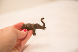 A small vintage bronze elephant sculpture with dark patina held to show its scale.