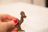 Vintage bronze rooster collectible held to show its compact size and detailed profile.