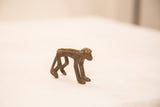 Vintage bronze monkey figurine in profile, showing its textured back and dark iron patina.