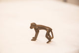 Side profile of a vintage monkey bronze gold weight on all fours.