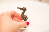 Vintage bronze pelican gold weight held in hand, demonstrating its petite, collectible size.