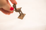 Vintage bronze pelican gold weight held in hand to illustrate its small, collectible size.