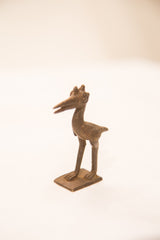 The dark, iron-like patina and incised wing details on a vintage pelican sculpture.