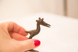 Small vintage bronze pelican sculpture held in hand to demonstrate its scale.