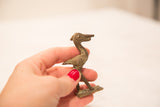 Collectible bronze pelican sculpture held, showing handmade texture and subtle green patina.