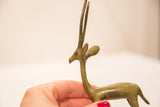 Profile view of the bronze gazelle's head, highlighting slender horns and green patina.