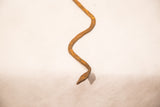 Vintage iron snake close-up, revealing rustic textured surface and aged patina.