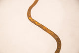 Detail of the vintage iron snake's rusted texture, displaying a unique aged orange and brown patina.