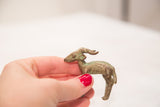 Vintage bronze impala ram held in hand, showing its small scale and textured patina.