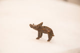 The textured back and dark finish of a small handmade bronze boar sculpture.