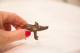 The small, handheld scale of a vintage African bronze boar gold weight.