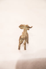 The back of a vintage bronze ram sculpture, showing its oxidized patina and curled horns.