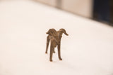 Frontal view of a vintage bronze ram sculpture highlighting its face and curled horns.
