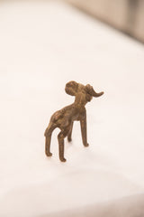 Rear quarter view of a vintage bronze ram, showing its handmade texture and curled horn.
