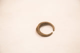 Angled view of a handmade bronze earring highlighting its textured, crescent shape.