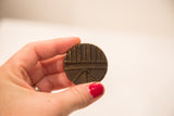 Handheld vintage bronze African gold weight with geometric pattern and dark patina.