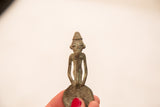 The braided beard and textured hat of a vintage male Ashanti bronze gold weight.