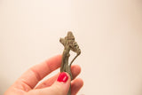 A hand holds a small Ashanti bronze figure, showing its profile and detailed braided beard.