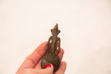 Back view of a bronze Ashanti gold weight showing its conical head and round spoon base.