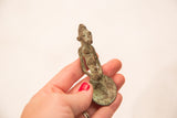 Vintage Ashanti gold weight held in hand, showing the scale and rich green patina.