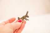 Hand holding small handmade bronze rabbit sculpture with green patina.