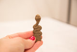 Collectible Ashanti bronze snake gold weight sculpture with shiny patina, held in hand.