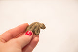 Small vintage bronze snake gold weight held in hand to demonstrate its scale.