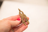 A vintage double-headed bronze snake weight held to show its handmade texture and size.