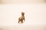 The antique bronze patina and handmade form of the meerkat figure from behind.