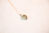 Angled view of the vintage African head pendant showing its blue oxidized patina and texture.