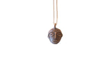Vintage African female head pendant with a dark textured patina on a simple chain.