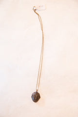 Vintage African head pendant with a dark patina shown hanging from its full chain.