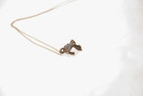 Angled view of the handmade frog pendant with a dark patina on a fine chain.