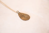Angled view of the vintage teardrop pendant's handmade geometric patterns and warm bronze patina.
